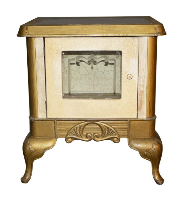 Antique gold cast iron warming oven with a glass-front door, decorative etched window, and curved feet.