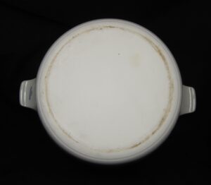 Bottom view of a ceramic soup pot with two side handles and blue-and-white decoration visible on the handles.