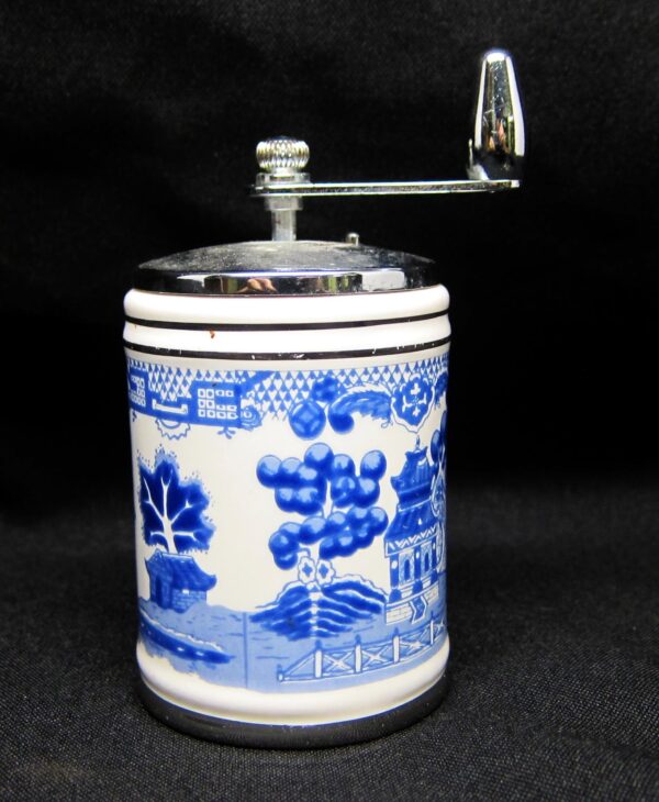 Ceramic shaker with a blue and white oriental design and a metal crank handle.