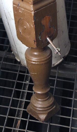 Traditional carved wooden staircase newel post with a bullseye detail, shown in a close-up view of the top section and turned base.