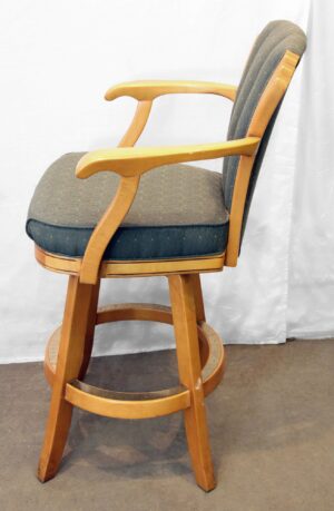Vintage Art Deco style bar chair with a high back, armrests, and footrest, shown in profile with green fabric upholstery and light wood tone frame.