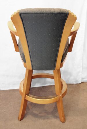 Back view of an Art Deco style high-back bar chair with armrests and a footrest ring, upholstered in green fabric and framed in light wood tone.