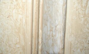 Close-up of a mirrored wood closet door showing the tan wood panel and the edge of the mirror section.