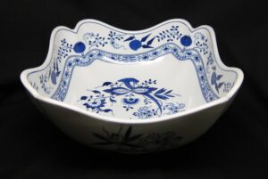 Blue and white ceramic vegetable bowl with a scalloped rim and blue floral pattern, shown at a front angle.
