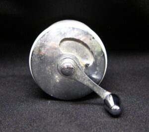 Shaker with a metal handle and round knob on a circular base, shown in close-up.