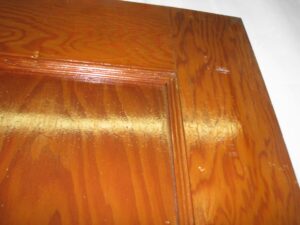 Close-up of a pine closet door showing the corner and raised panel detail with a dark wood tone finish.