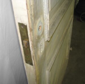 Close-up of a white wood passage door showing the latch edge, strike plate, and one raised panel detail.