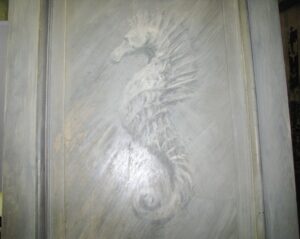 Close-up of a white wood passage door showing one raised panel with decorative carved detail.