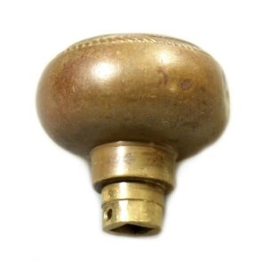 Antique bronze passage door knob with a rounded top and a short stem, shown in close-up as a single knob with visible wear and lettering on the center.