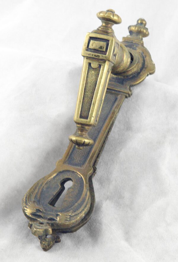 Antique brass lever handle set with a matching back plate, shown in close-up from an angle.
