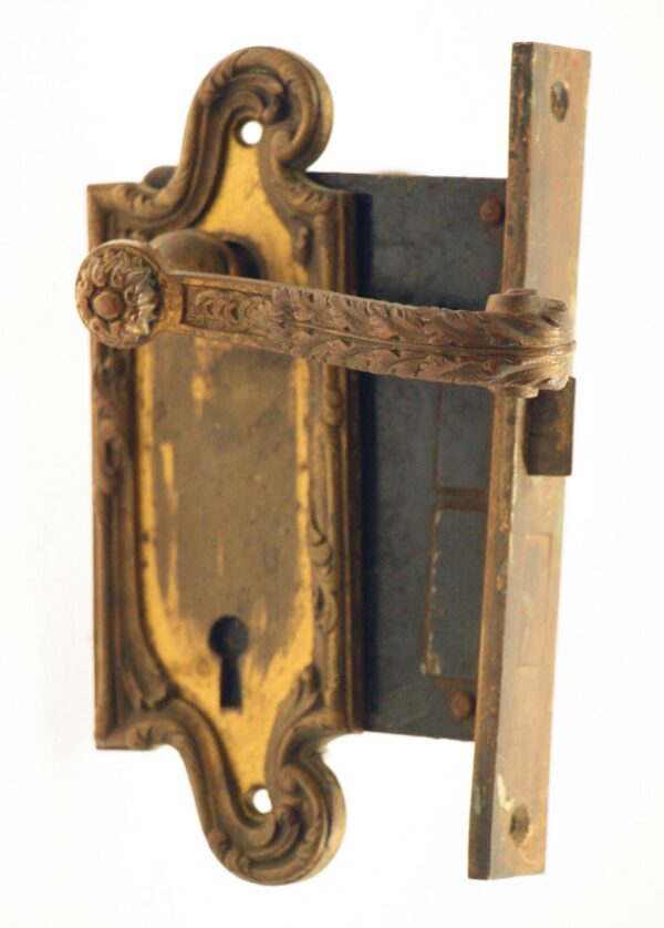 Ornate antique bronze mortise lock set with a decorative lever, back plate, and keyhole visible in close-up.