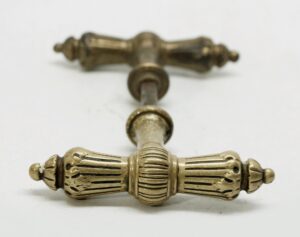 Set of bronze T lever door knobs with one spindle, shown in a close-up of the ornate gold-finished hardware.