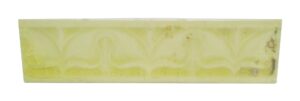 Light yellow ceramic decorative border tile with a crackled surface and worn imperfections.