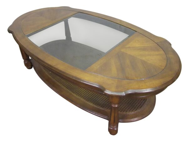 Oval oak coffee table with a center glass top and lower caned shelf, shown at an angle.