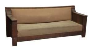 Empire-style couch with studded beige upholstery and a dark wood frame, shown from the front with visible wear from age and use.