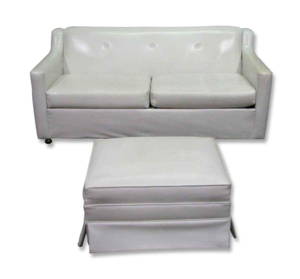 White mid century two-seat sofa with a matching ottoman shown together.