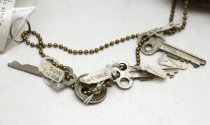 Antique bank safe deposit lock keys on ball chains with several tagged keys visible.