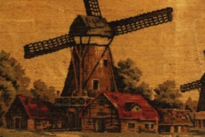 Wood-framed fabric wall art showing a Holland windmill scene with brown and orange tones.