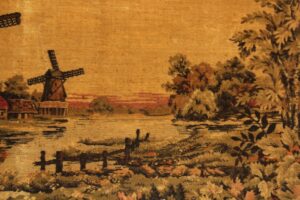 Wood-framed fabric portrait showing an old windmill scene in Holland, with brown and orange tones visible in the landscape.