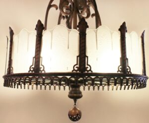 Art Deco chandelier with an antique bronze frame and frosted glass panels, shown in a close-up of the circular lower section and central finial.