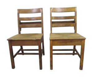 Pair of antique schoolhouse chairs with square wooden frames and woven seats, shown side by side in a light wood tone.