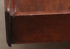Close-up of a side table showing the dark wood frame and front panel edge with visible wear.