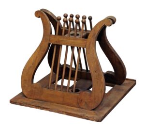 Carved wooden music or book stand with a decorative scroll frame and vertical slats, shown in a medium wood tone.