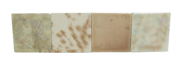 Set of four square ceramic tiles shown side by side, each with a warm mixed color and visible age-related imperfections.