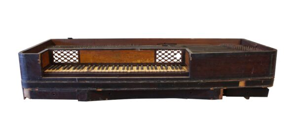 Antique piano forte keyboard in dark wood tone, shown open to reveal the keys and interior string area.