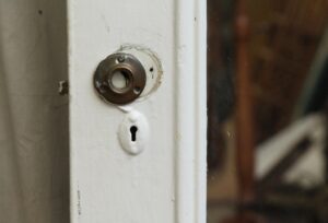 Close-up of a white mirrored closet door showing the round knob plate and keyhole on the painted wood edge.