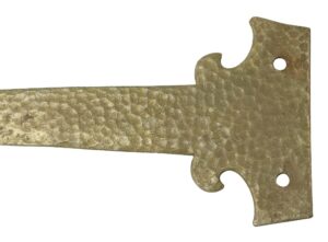 Close-up of a hammered cast iron door strap hinge with a textured finish and two mounting holes on the backplate.