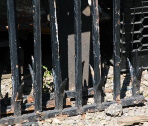 Close-up of a wrought iron fence section with split finials and visible cast detail on the bars.