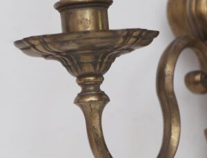 Close-up of an antique bronze wall sconce with an urn-shaped center and decorative curved arm detail.