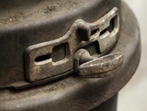 Close-up of a cast iron wood burner latch and vent detail on a black surface.
