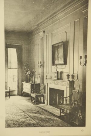 Framed photograph of a 1900s residence interior, showing a fireplace, chairs, and wall paneling within the image.