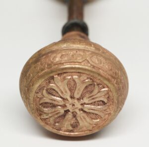 Close-up of a brass door knob with a four-petal floral rosette design on the end.