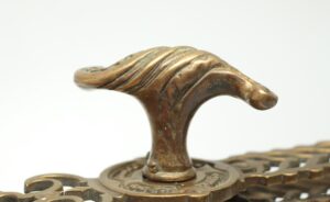 Close-up of an antique bronze serpentine door handle with a twisted top and ornate backplate detail.