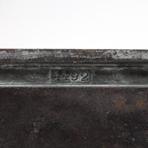 Close-up of a bronze back plate showing the stamped number 4492 and weathered antique finish.