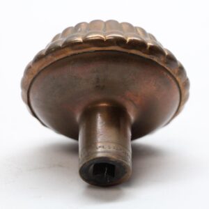 Antique bronze door knob shown from below with a radial ridged top and worn surface finish.