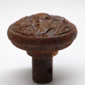 Close-up of an antique cast iron door knob with a swirl top and visible rust and wear.