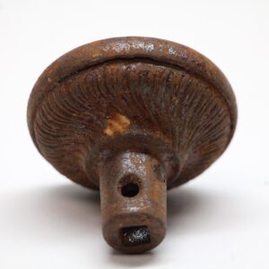 Close-up of a cast iron door knob with a swirl design and visible rust and wear.