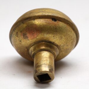 Antique brass door knob shown from the back, with a square spindle opening and visible surface wear.