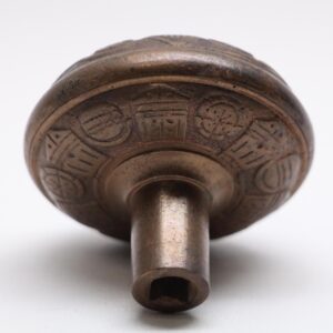 Antique bronze door knob with engraved circular pattern and square spindle opening, shown in close-up from below.