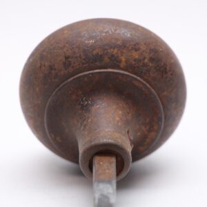 Close-up of a cast iron passage door knob with a dark black patina and visible surface wear, shown from the back with the square spindle opening.