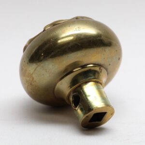 Close-up of a polished brass door knob with a short stem and visible surface wear.