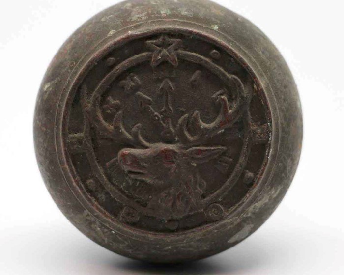 A round, dark metal knob features a stag’s head, crossed arrows, star, and horseshoe—detailed design ideal for antique collectors or historic architecture settings.