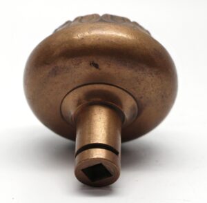 Close-up of an antique bronze door knob showing the underside and square spindle opening.