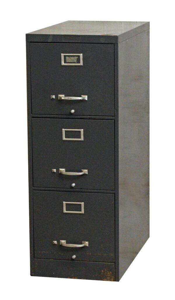 Gray metal file cabinet with three drawers, shown in a front-left view with rectangular label holders and pull handles on each drawer.