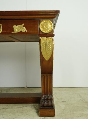 Close-up of a mahogany desk corner with gilt bronze appliques and a carved leg.