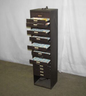 Tall narrow brown metal cabinet with multiple open drawers filled with small parts.